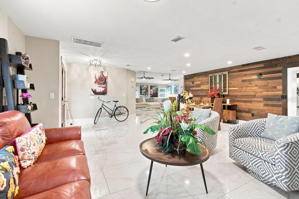 A living room features white tile floors, a leather sofa, and a wood-paneled accent wall — 17933 EAGLE LANE, LUTZ, FL