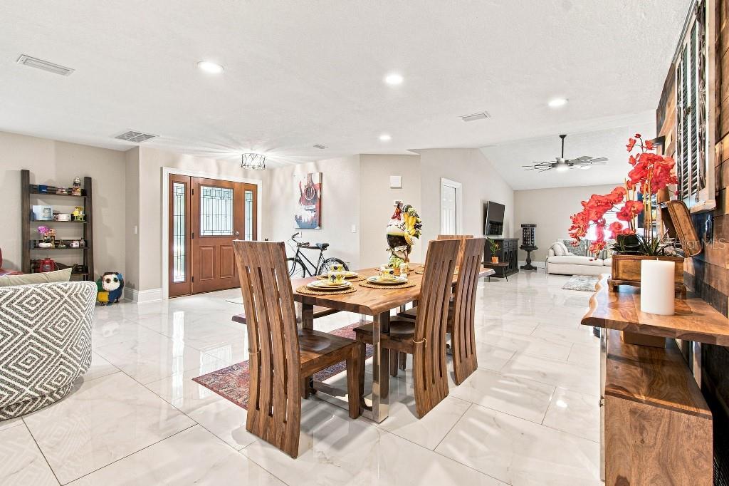 A dining area with a wooden table and chairs sits on a white tiled floor — 17933 EAGLE LANE, LUTZ, FL