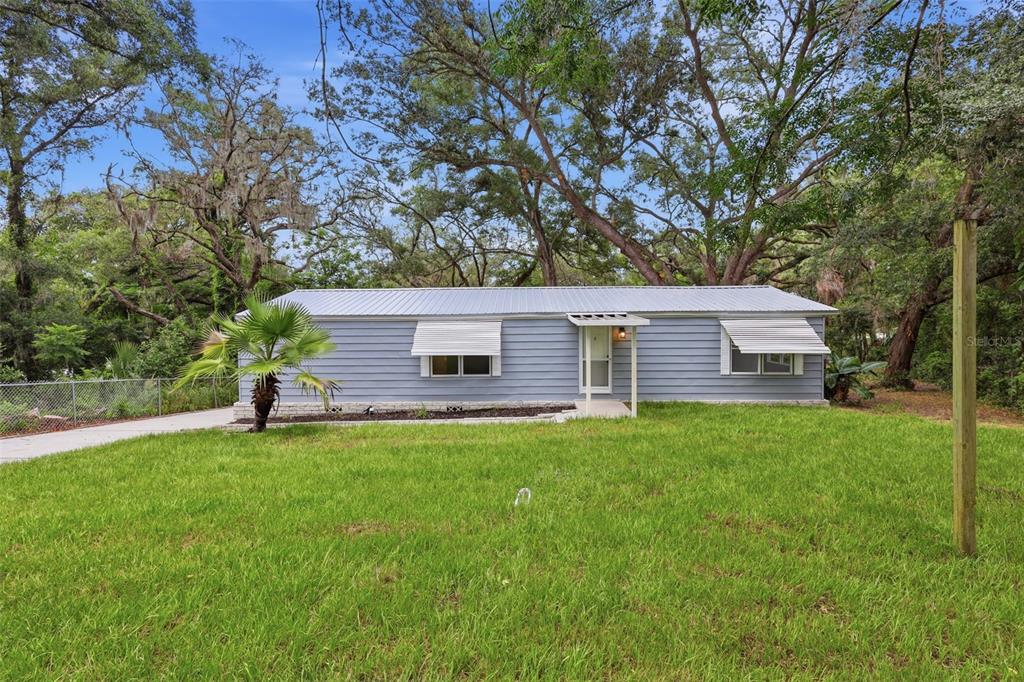 A single-story light blue house with a metal roof sits on a grassy lot — 403 ACORN CIRCLE, FRUITLAND PARK, FL