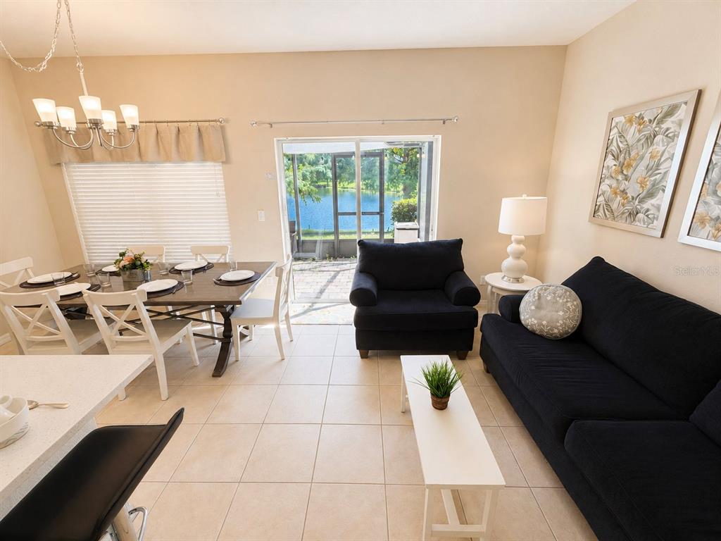 A dining area and living room with tile floors overlook a lake through sliding doors — 2379 CARAVELLE CIRCLE, KISSIMMEE, FL