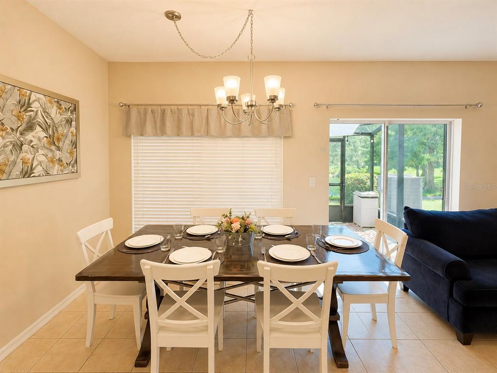 A dining room features a dark wood table, white chairs, a chandelier, and sliding doors — 2379 CARAVELLE CIRCLE, KISSIMMEE, FL