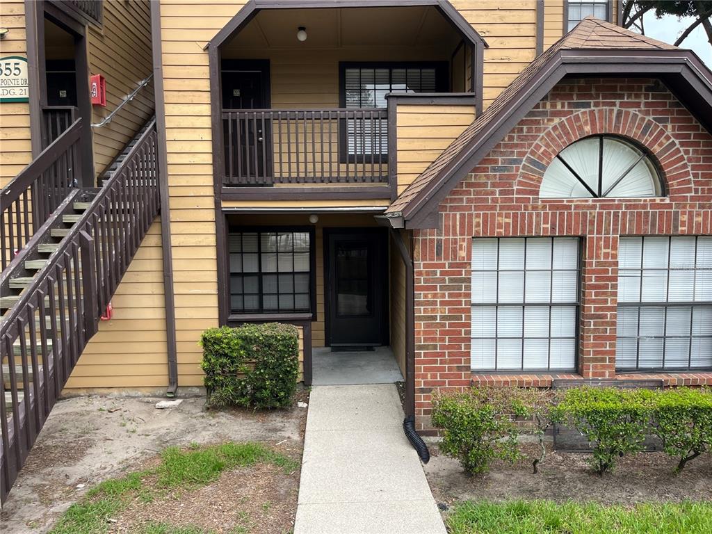 A two-story apartment building exterior features tan siding, brick accents, and a concrete walkway — 355 LAKEPOINTE DRIVE UNIT 102, ALTAMONTE SPRINGS, FL