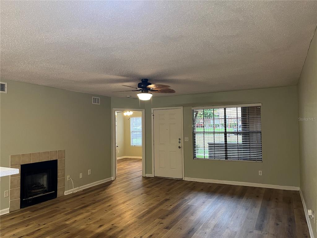A living room features wood-look flooring, a fireplace, a ceiling fan, and an entry door — 355 LAKEPOINTE DRIVE UNIT 102, ALTAMONTE SPRINGS, FL