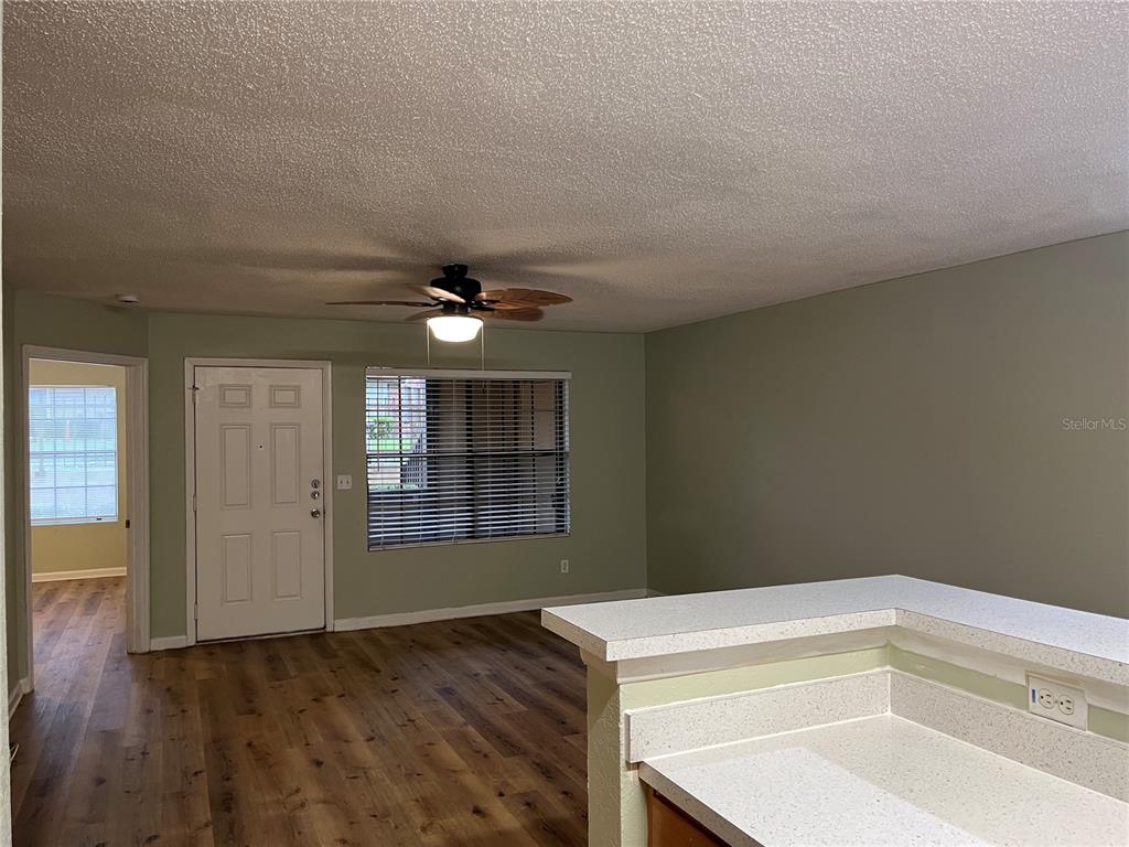 A living room with wood-look flooring, a ceiling fan, and an adjacent kitchen counter — 355 LAKEPOINTE DRIVE UNIT 102, ALTAMONTE SPRINGS, FL