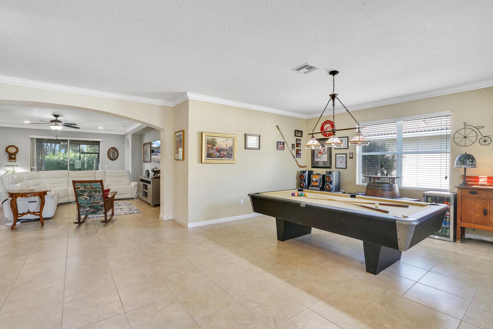 A game room with a pool table and a living area visible through an archway — 9328 Silent Oak Circle, West Palm Beach FL 33411, WEST PALM BEACH, FL