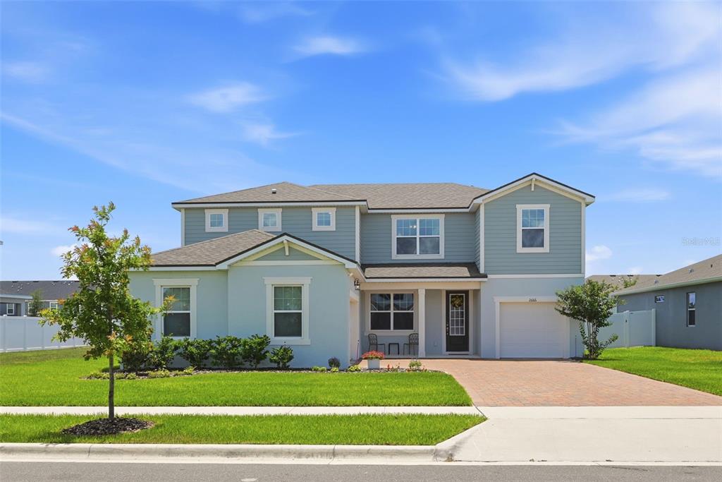 A two-story house with light blue siding, a brick driveway, and a front porch — 2666 GINSENG IVY STREET, APOPKA, FL