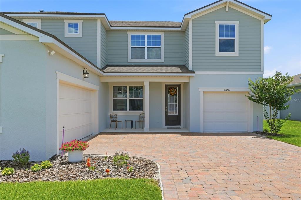 A two-story house with light blue siding, a brick driveway, and two garage doors — 2666 GINSENG IVY STREET, APOPKA, FL