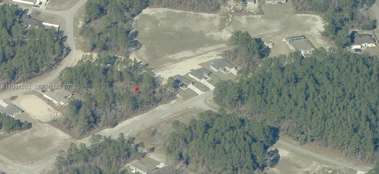 An aerial view shows a vacant wooded lot marked with a red pin near houses — 0 SW 131st Lane, Ocala FL 34473, OCALA, FL