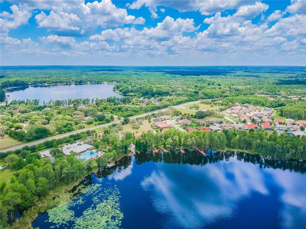 Aerial view of a residential neighborhood featuring two lakes, a community pool, and lush trees — 0 PURDUE STREET, NEW PORT RICHEY, FL
