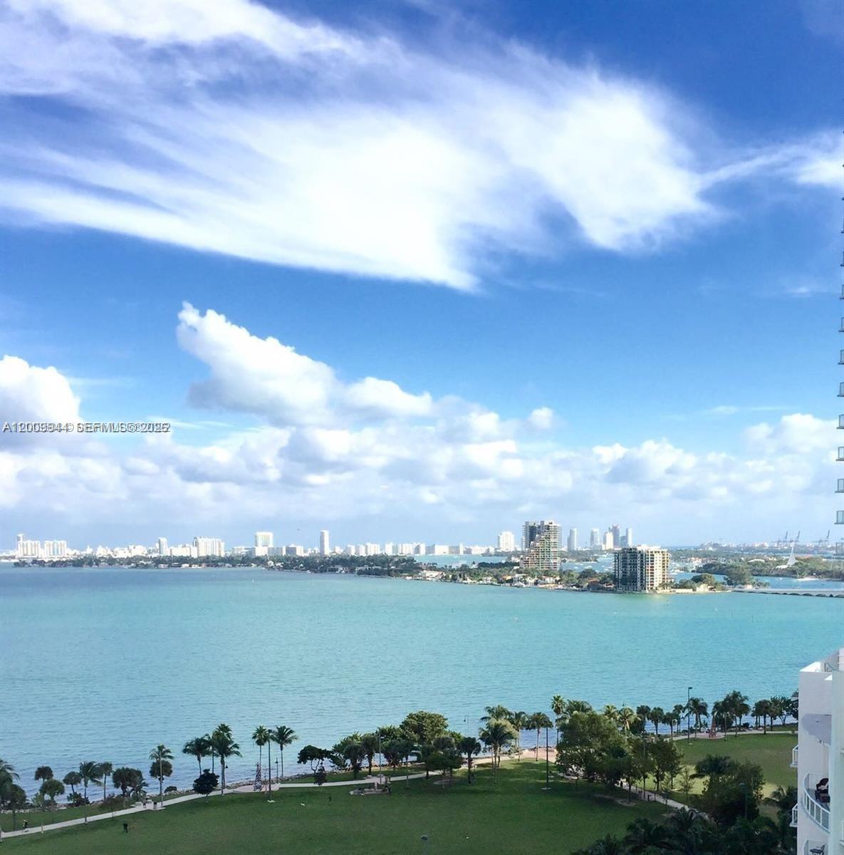 An elevated view of a bay with a park, palm trees, and distant city buildings — 2000 N Bayshore Dr # 1606, Miami FL 33137, MIAMI, FL