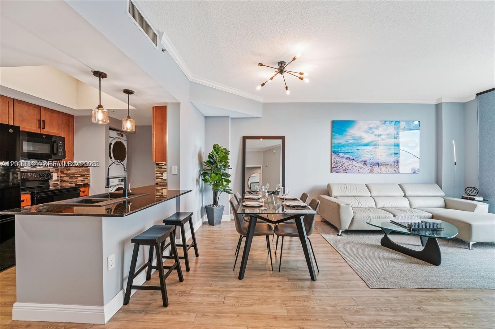 An open-concept living and dining area features a kitchen island, modern lighting, and wood flooring — 2000 N Bayshore Dr # 1606, Miami FL 33137, MIAMI, FL