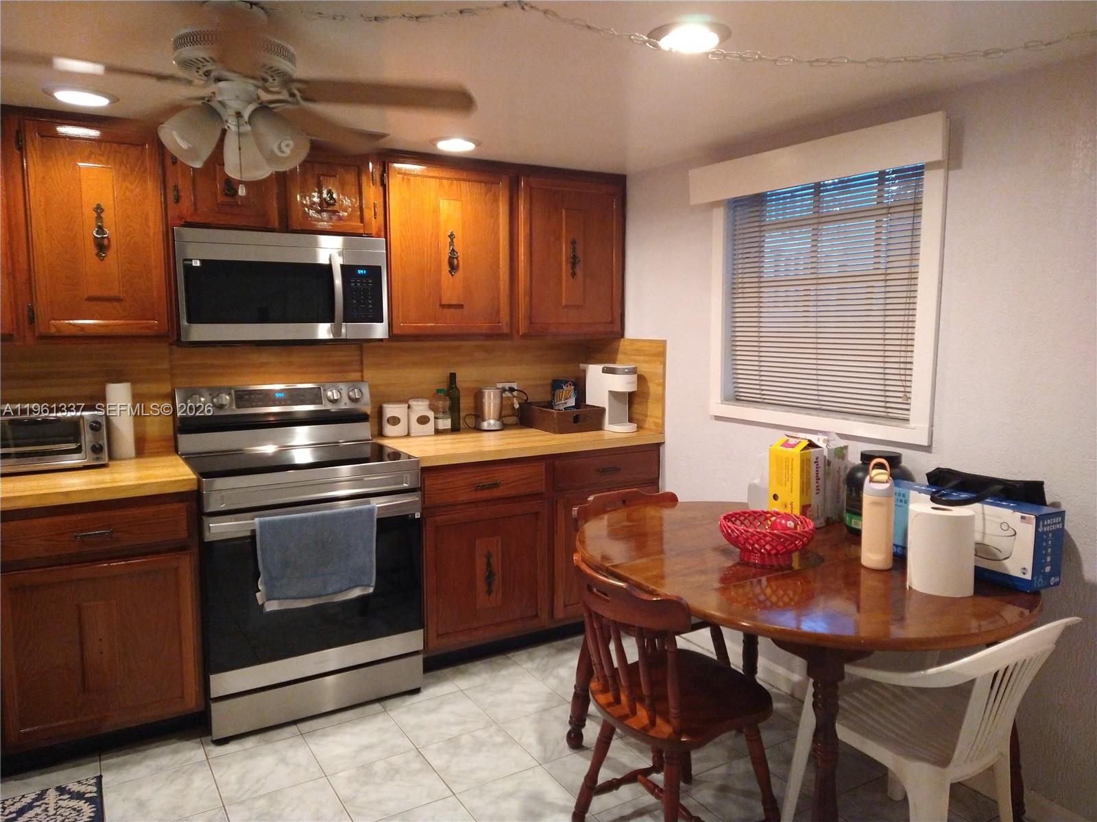 A kitchen features wood cabinets, stainless steel appliances, a tile floor, and a dining table — 7554 Stirling Rd # 105, Davie FL 33024, DAVIE, FL