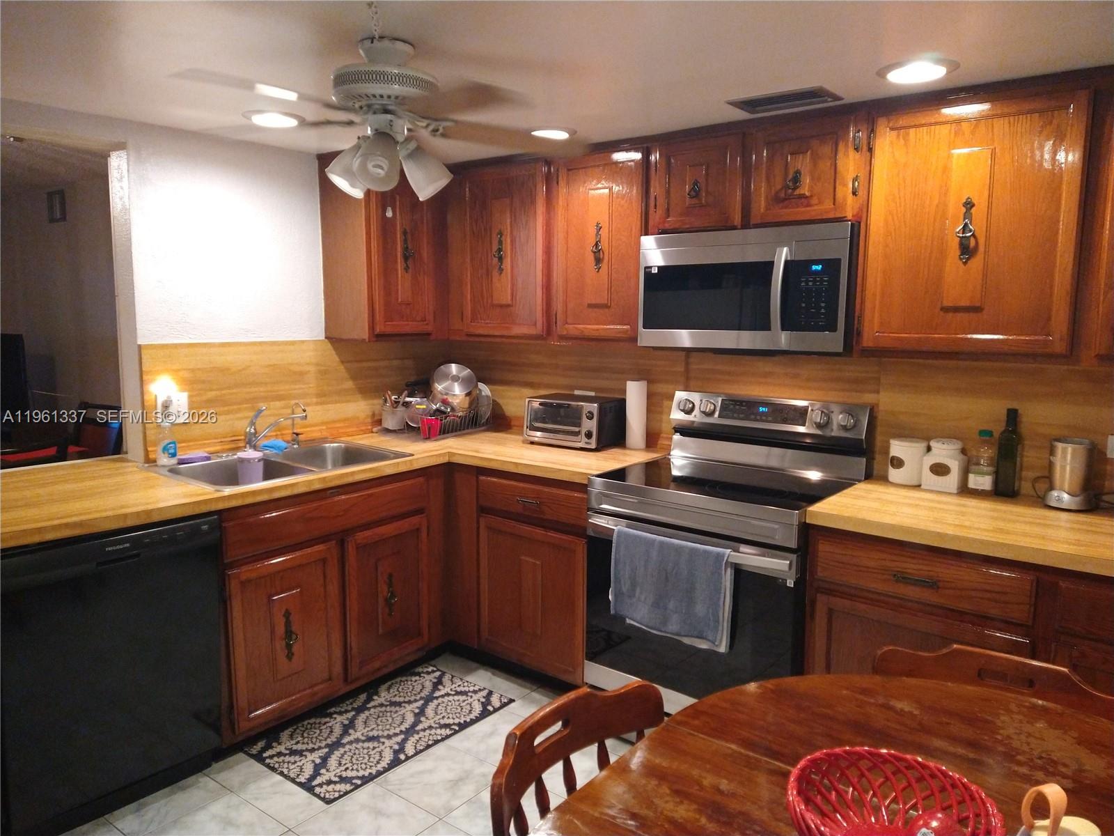 A kitchen features wood cabinets, stainless steel appliances, and light-colored countertops — 7554 Stirling Rd # 105, Davie FL 33024, DAVIE, FL