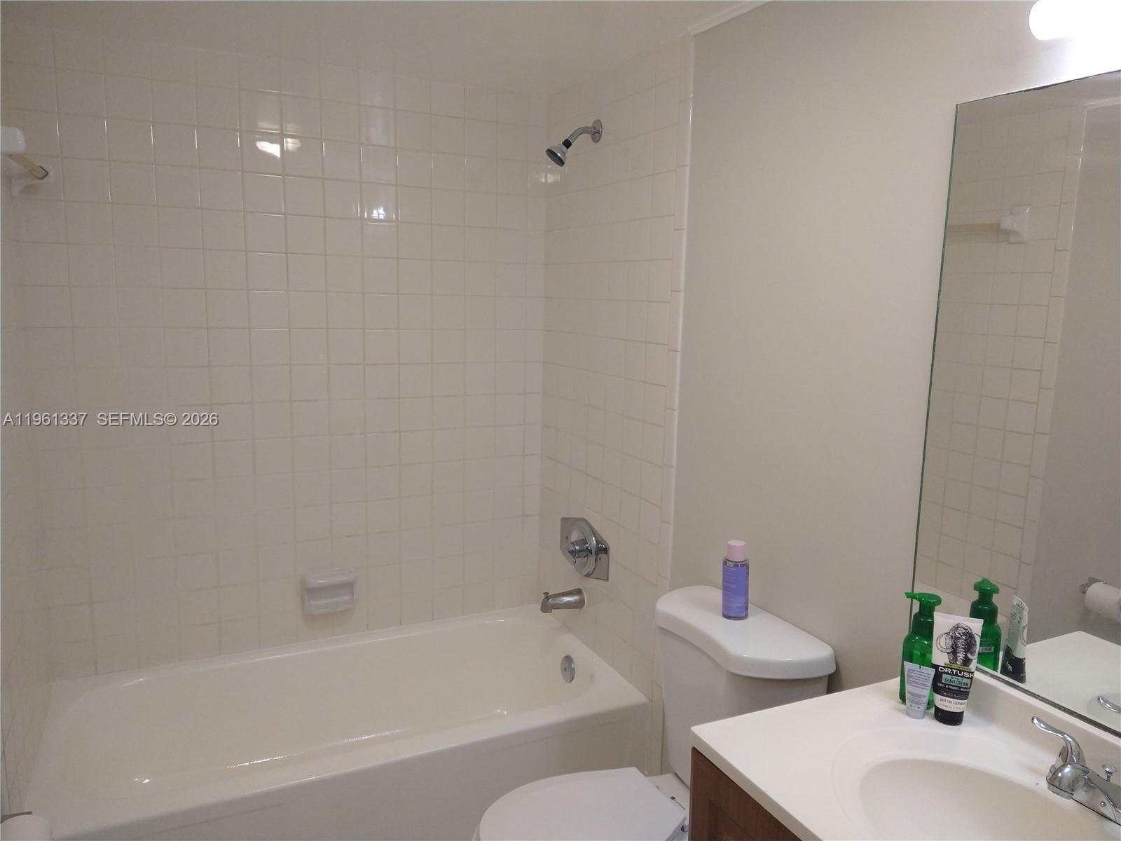 A bathroom features a white bathtub with tiled walls, a toilet, and a vanity — 7554 Stirling Rd # 105, Davie FL 33024, DAVIE, FL