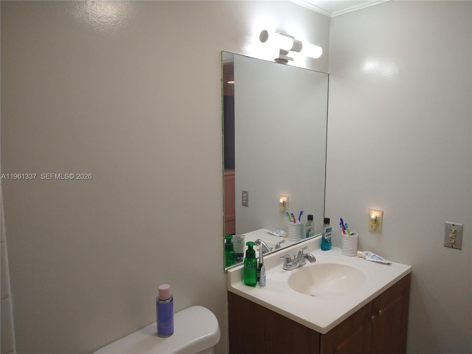 A bathroom features a vanity with a sink, a mirror, and a wall-mounted light fixture — 7554 Stirling Rd # 105, Davie FL 33024, DAVIE, FL
