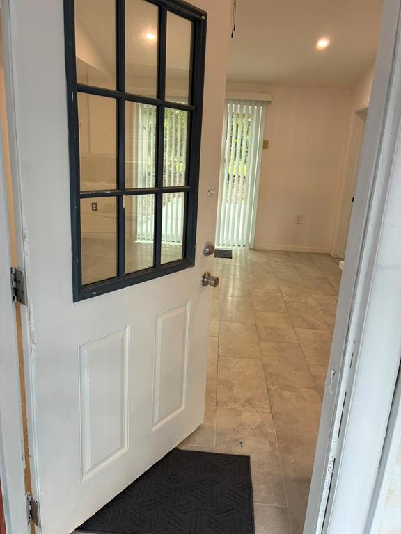 A white door with a glass pane opens into a room with light-colored tile flooring — 106 PENNSYLVANIA AVENUE, POMONA PARK, FL