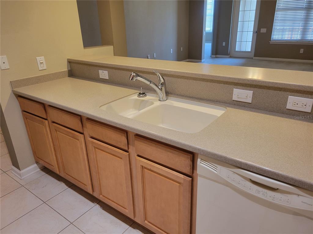 A kitchen sink with a faucet is set into a countertop above wooden cabinets — 7905 N SEMINOLE BOULEVARD UNIT 3404, SEMINOLE, FL