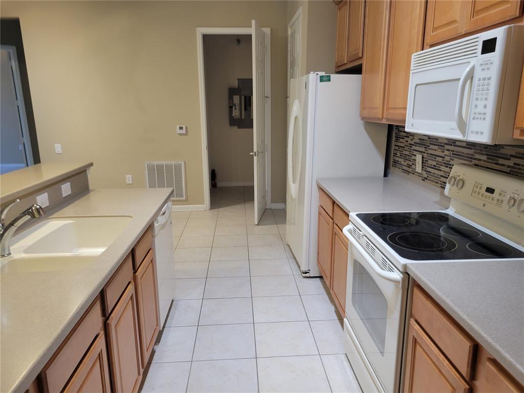 A kitchen features light wood cabinets, white appliances, a tiled floor, and a breakfast bar — 7905 N SEMINOLE BOULEVARD UNIT 3404, SEMINOLE, FL