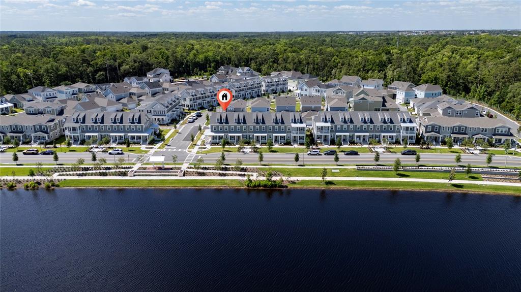 An aerial view shows a row of townhouses situated along a lake and wooded area — 2426 CELEBRATION BOULEVARD, KISSIMMEE, FL
