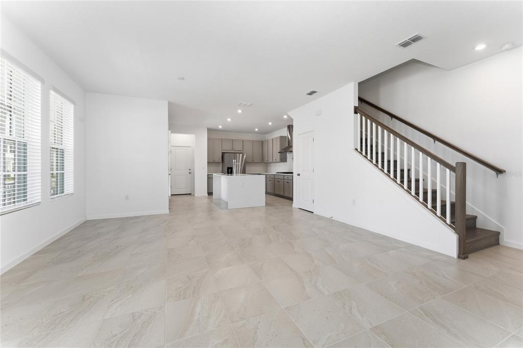 An open-concept living area features light tile flooring, a kitchen with an island, and stairs — 2426 CELEBRATION BOULEVARD, KISSIMMEE, FL