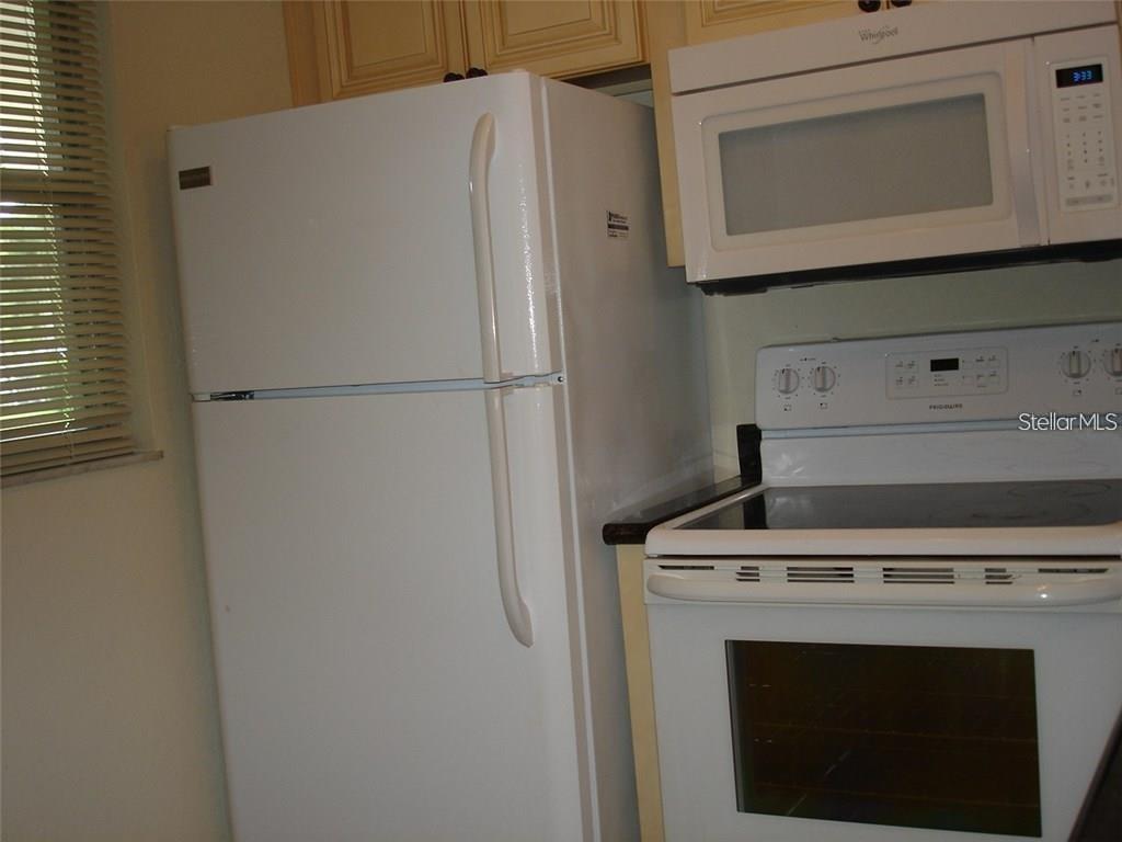 A white refrigerator stands next to a white electric range and an over-the-range microwave — 7211 W COUNTRY CLUB DRIVE N UNIT 133, SARASOTA, FL