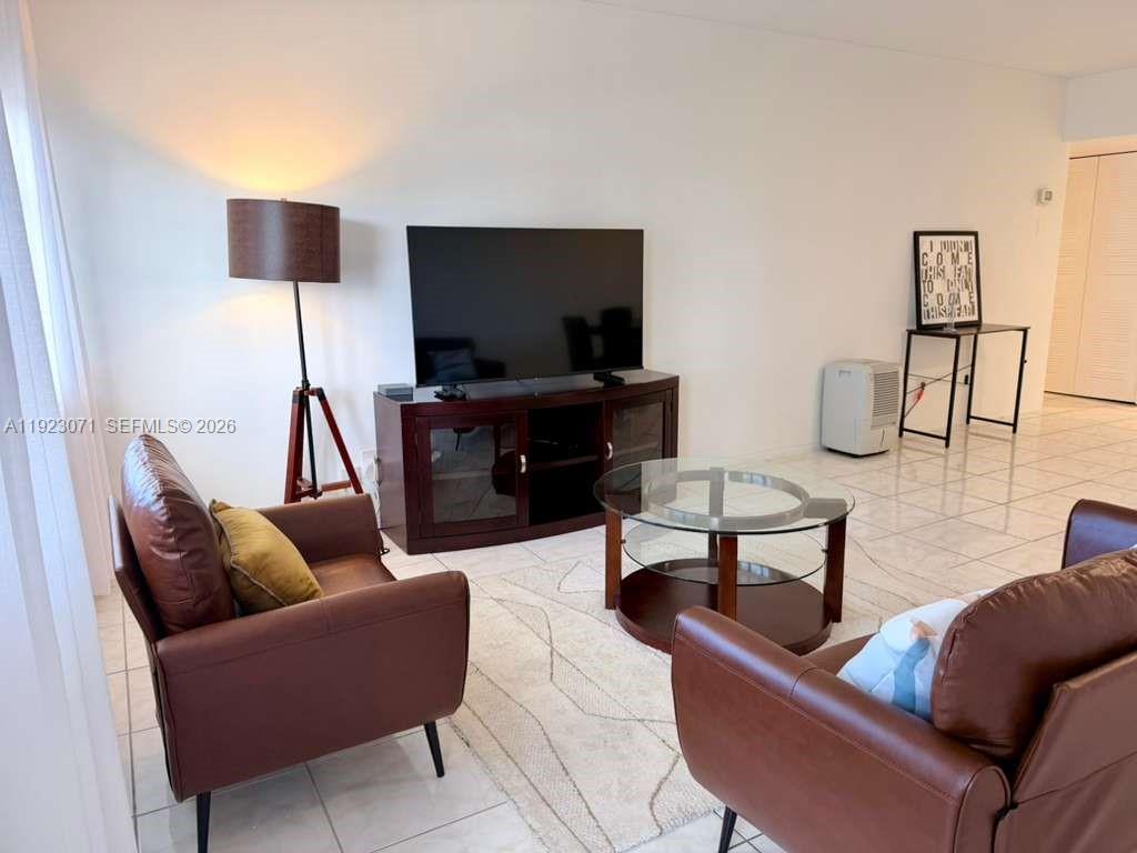 A living room features brown leather armchairs, a glass coffee table, and a television console — 100 Lincoln Rd # 541, Miami Beach FL 33139, MIAMI BEACH, FL