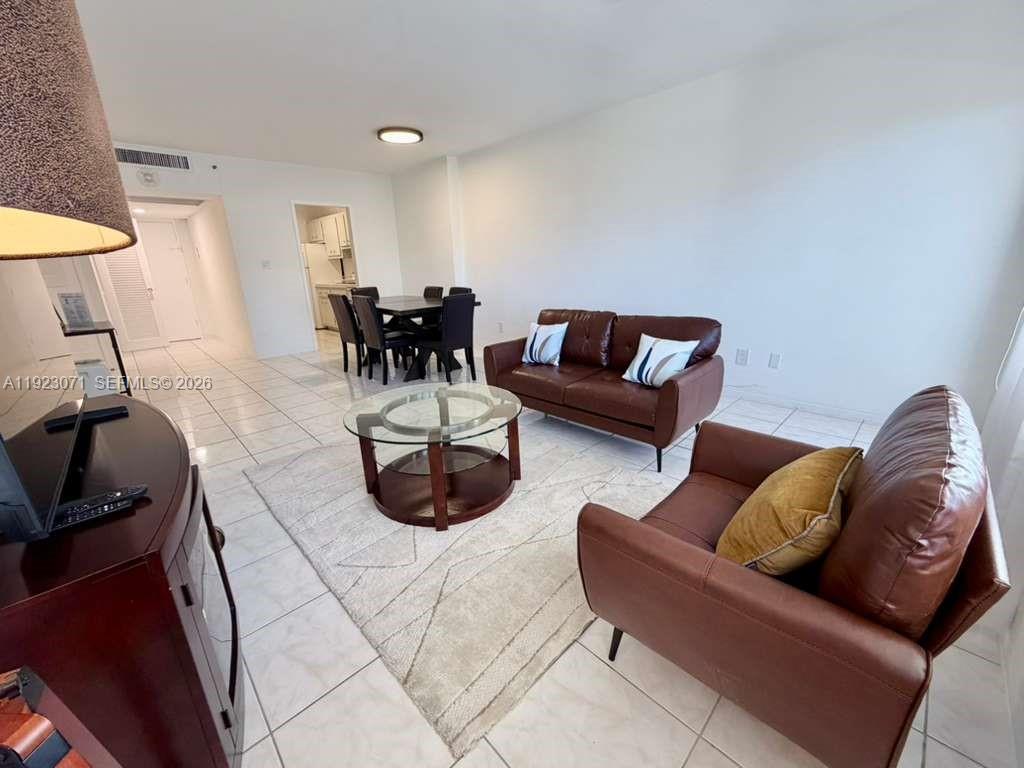 A living and dining area features white tile floors, brown leather furniture, and a rug — 100 Lincoln Rd # 541, Miami Beach FL 33139, MIAMI BEACH, FL