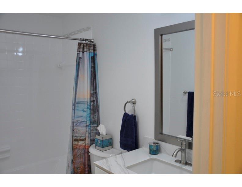 A bathroom features a white vanity with a marble countertop, a mirror, and a shower — 2630 WOODGATE LANE UNIT G3, SARASOTA, FL