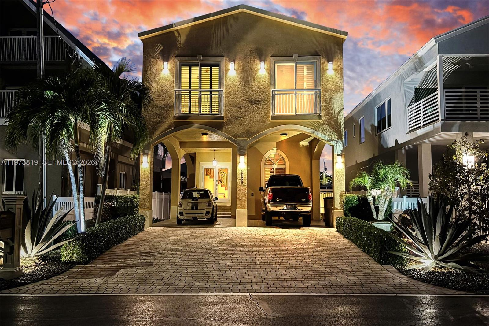 A two-story house with a paved driveway, two parked vehicles, and arched ground-level entryways — 226 Normandy Dr, Tavernier FL 33070, TAVERNIER, FL