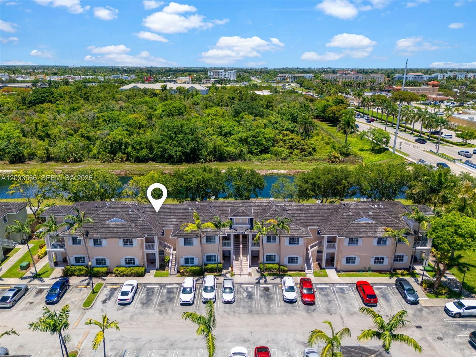 An aerial view shows a two-story apartment building with a parking lot and a canal — 2741 NE 4th St # 202, Homestead FL 33033, HOMESTEAD, FL