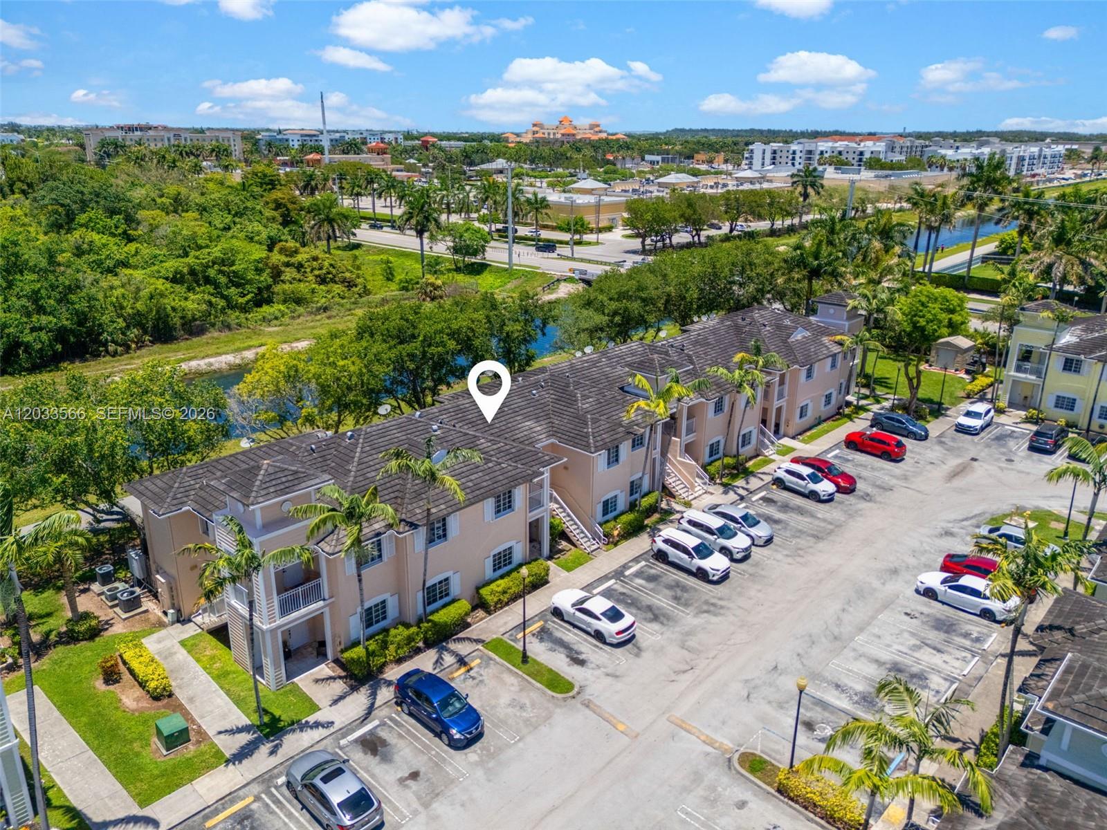 An aerial view shows a multi-story apartment building with a parking lot and surrounding greenery — 2741 NE 4th St # 202, Homestead FL 33033, HOMESTEAD, FL