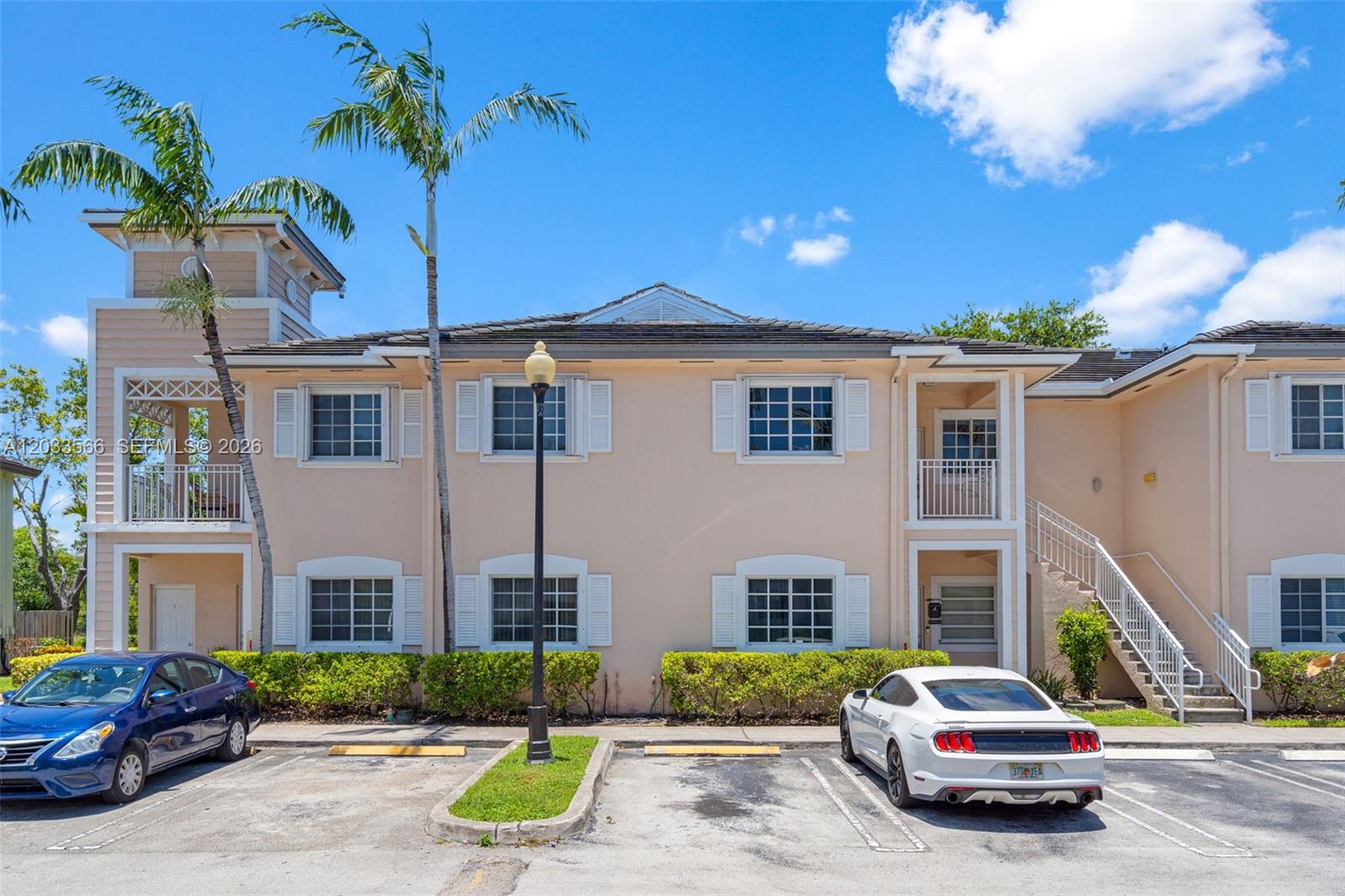 A two-story peach-colored apartment building features white shutters, balconies, and a parking lot — 2741 NE 4th St # 202, Homestead FL 33033, HOMESTEAD, FL