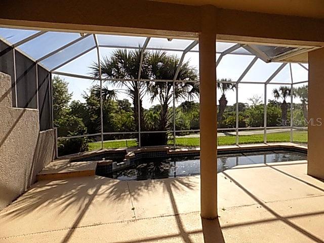 A screened-in patio features a swimming pool with a spa overlooking a grassy backyard — 4641 SAMOSET DRIVE, SARASOTA, FL
