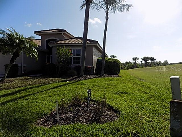 A two-story house with a tile roof sits next to a grassy golf course — 4641 SAMOSET DRIVE, SARASOTA, FL