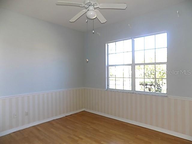 An empty room features light blue walls, striped wainscoting, wood flooring, and a ceiling fan — 4641 SAMOSET DRIVE, SARASOTA, FL