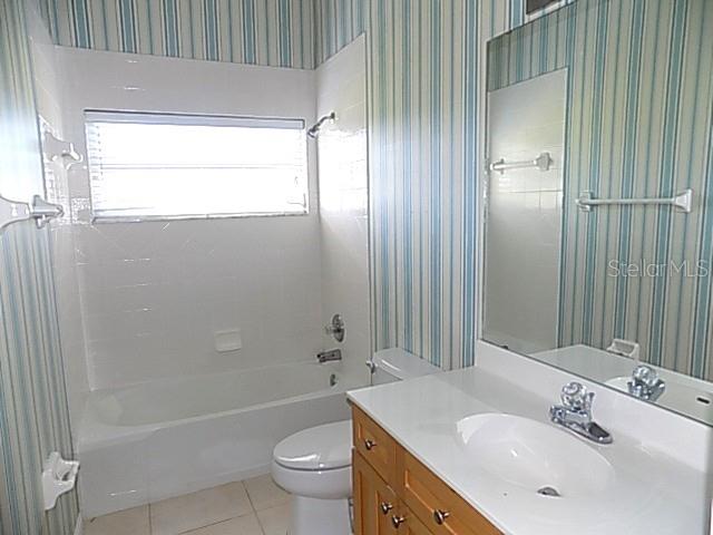 A bathroom features a white tub-shower combo, a wooden vanity, and blue-striped wallpaper — 4641 SAMOSET DRIVE, SARASOTA, FL