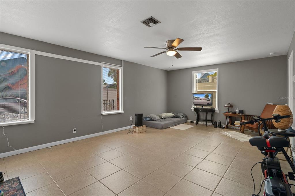 A spacious room with gray walls, tile flooring, a ceiling fan, and three windows — 5437 29TH AVENUE S, GULFPORT, FL
