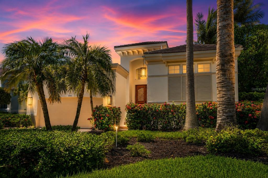 A single-story house with a garage, palm trees, and a sunset sky in the background — 3526 FAIR OAKS LANE, LONGBOAT KEY, FL