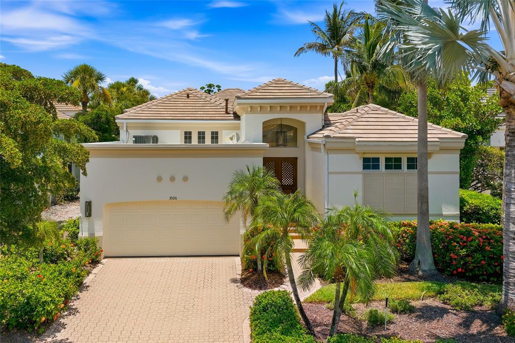 A single-story house with a beige stucco exterior, a tiled roof, and a paved driveway — 3526 FAIR OAKS LANE, LONGBOAT KEY, FL