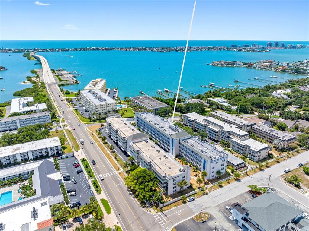 An aerial view shows a multi-story apartment complex near a bridge and the ocean — 139 BLUFF VIEW DRIVE UNIT 407, BELLEAIR BLUFFS, FL