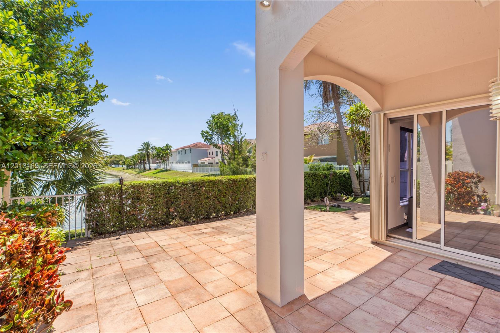 A tiled patio features a covered archway, sliding glass doors, and a view of water — 3760 SW 51st St, Hollywood FL 33312, HOLLYWOOD, FL