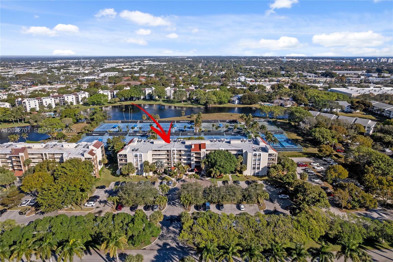 An aerial view shows a multi-story apartment building situated next to a lake and tennis courts — 825 Egret Cir # 504, Delray Beach FL 33444, DELRAY BEACH, FL