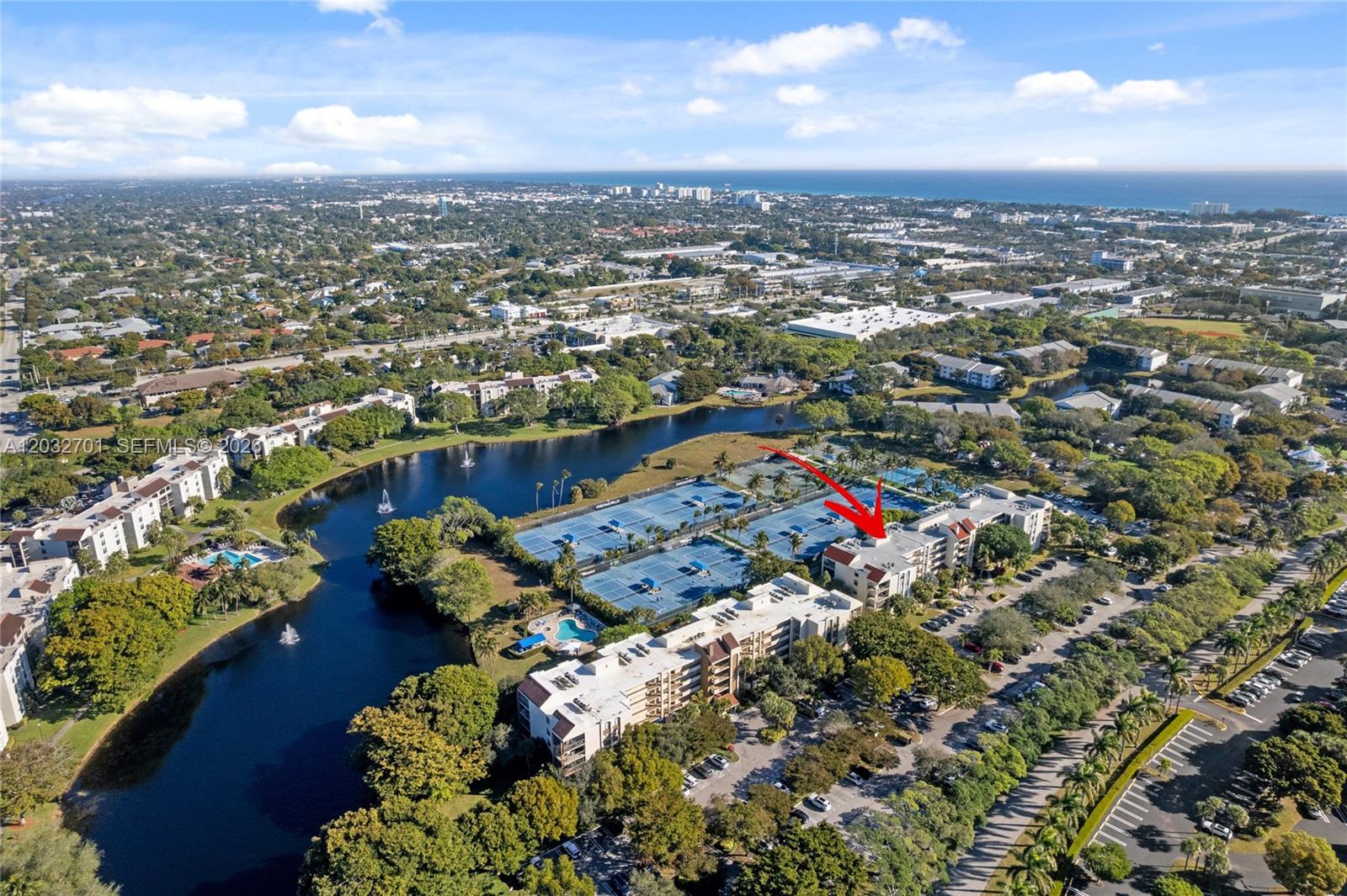 An aerial view shows a multi-story residential building complex with tennis courts and a lake — 825 Egret Cir # 504, Delray Beach FL 33444, DELRAY BEACH, FL