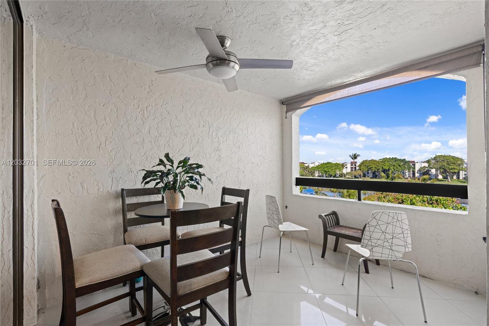 A covered balcony features a dining set, additional chairs, a ceiling fan, and outdoor views — 825 Egret Cir # 504, Delray Beach FL 33444, DELRAY BEACH, FL