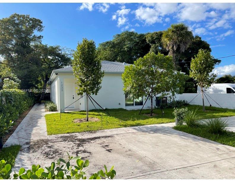 A white single-story house features a concrete driveway, a front lawn, and young trees — 920 NW 81st St, Miami FL 33150, MIAMI, FL
