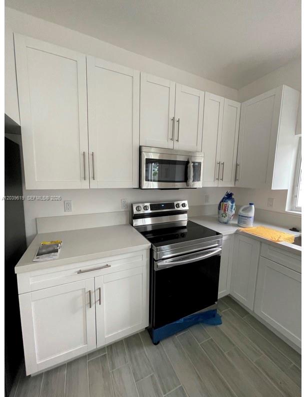 A kitchen features white shaker cabinets, stainless steel appliances, and light-colored countertops — 920 NW 81st St, Miami FL 33150, MIAMI, FL