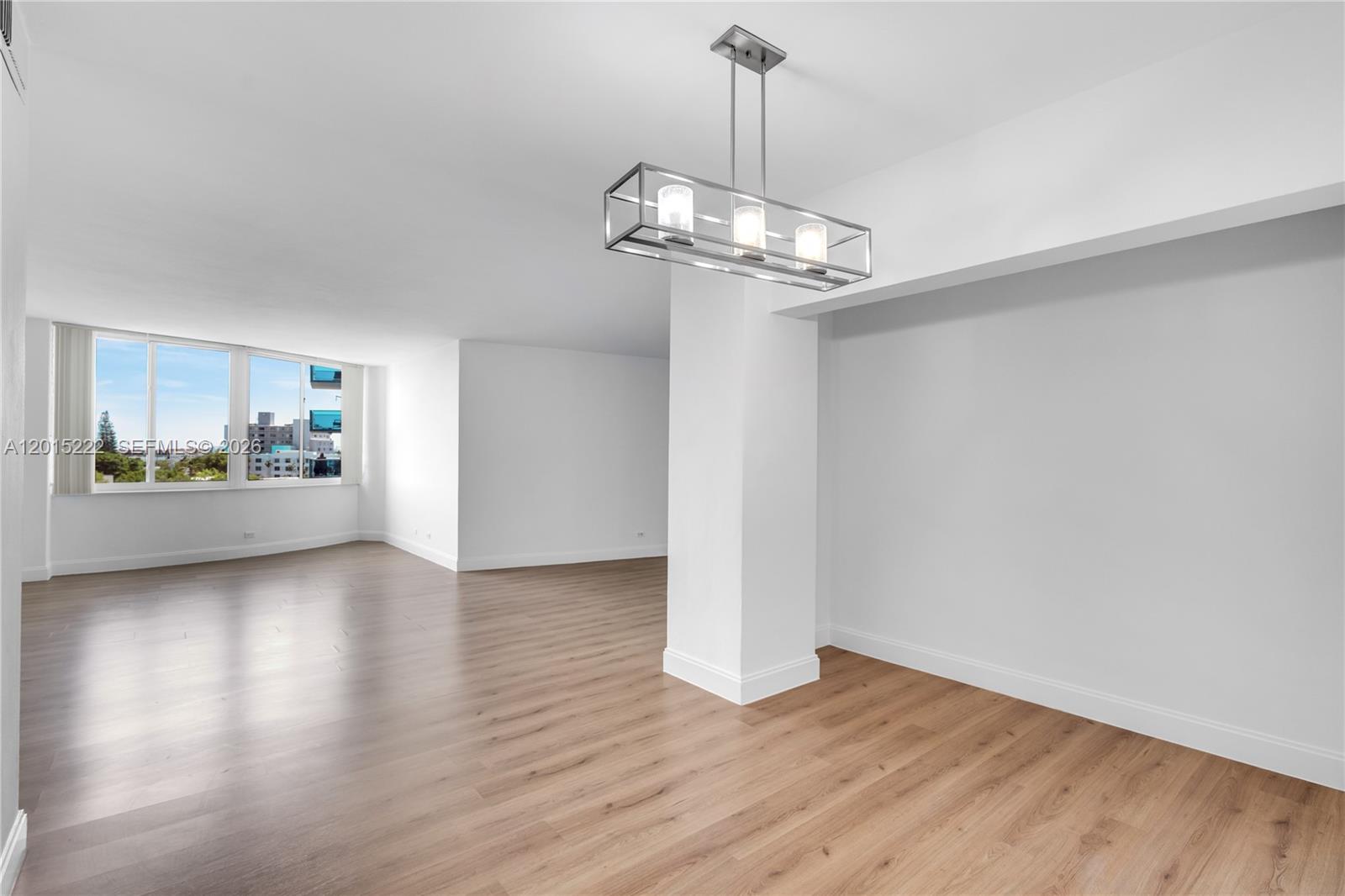 An empty room with light wood flooring, white walls, and a modern rectangular pendant light — 7441 Wayne Ave # 4G, Miami Beach FL 33141, MIAMI BEACH, FL