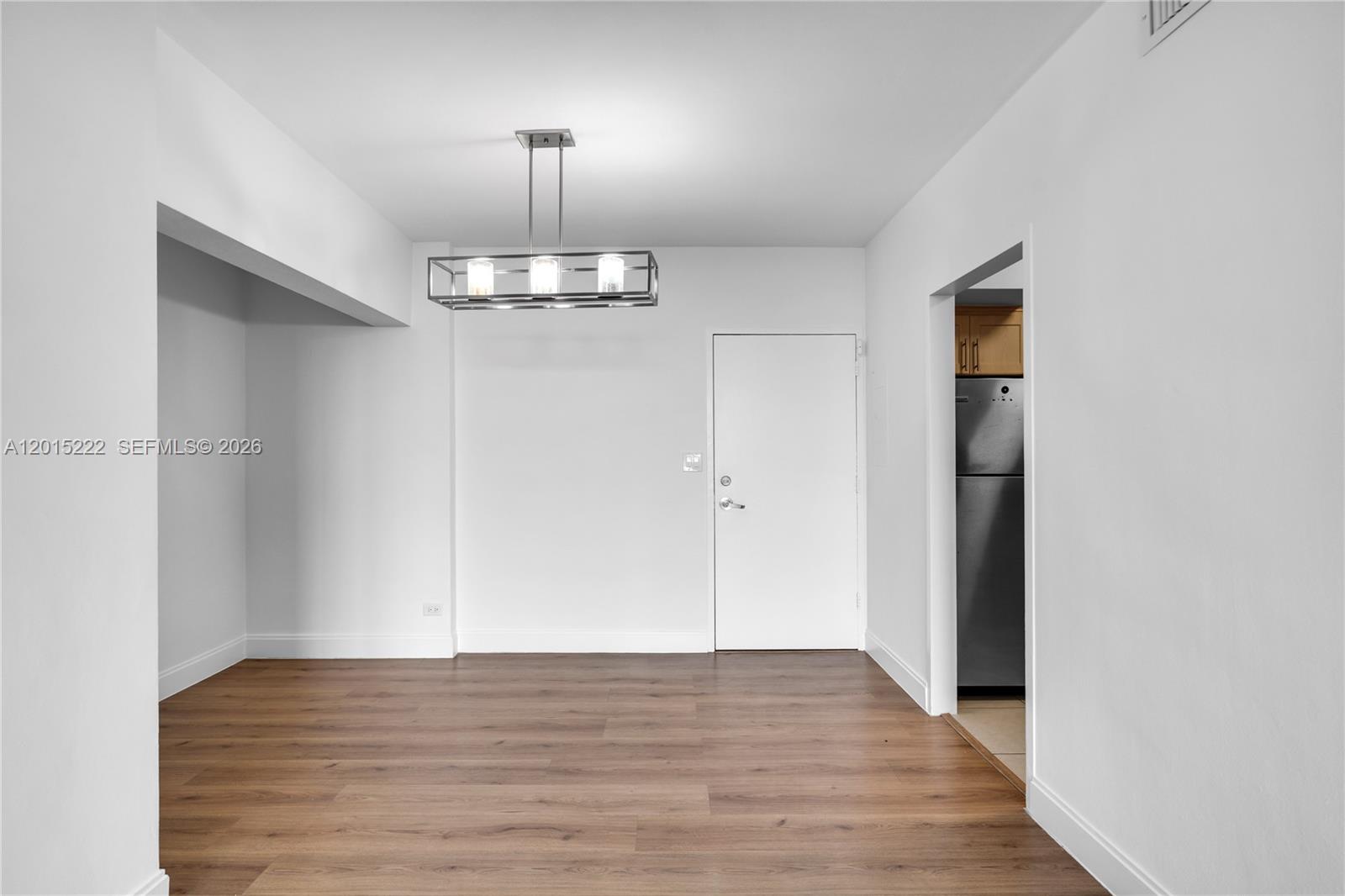 This dining area features wood-look flooring, white walls, and a modern rectangular pendant light — 7441 Wayne Ave # 4G, Miami Beach FL 33141, MIAMI BEACH, FL