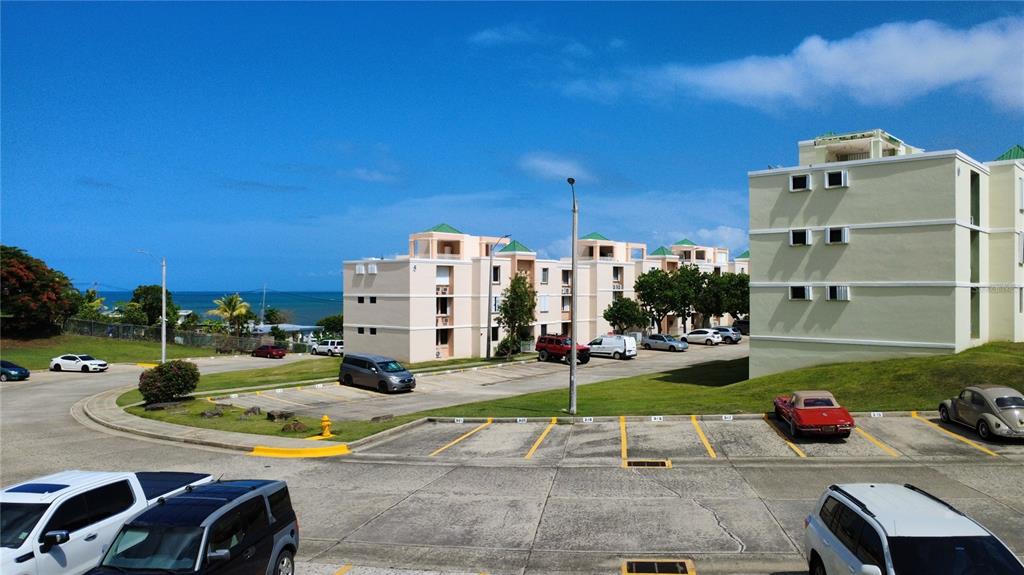 An elevated view shows apartment buildings with parking lots and a distant ocean view — Cond Vista Real E 3 -23 -B VILLAGE E UNIT 23, FAJARDO, PR