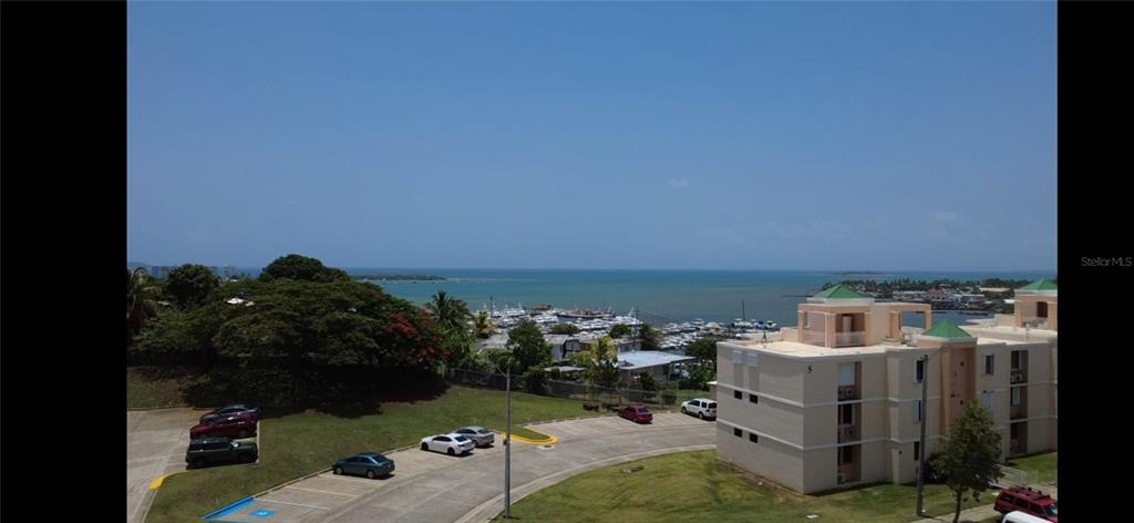 An elevated view shows a parking lot, a multi-story apartment building, and a coastal harbor — Cond Vista Real E 3 -23 -B VILLAGE E UNIT 23, FAJARDO, PR